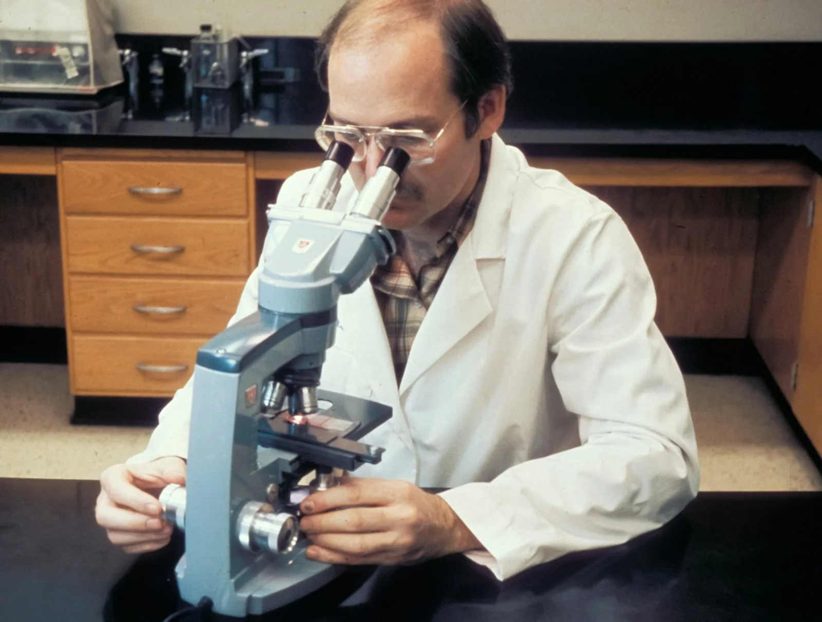 A researcher examining a sample through a microscope